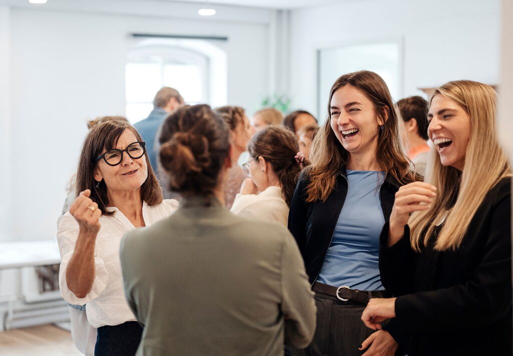 Teamcoach Ausbildung Online Lachende Teilnehmerinnen im Gespräch während einer Ausbildungspause